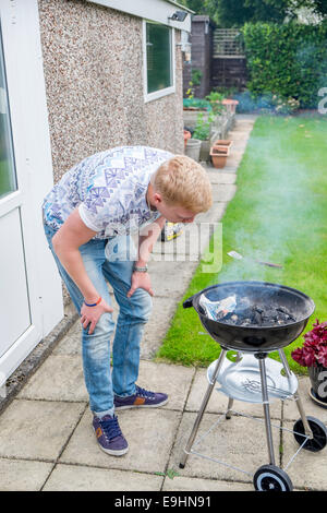 Giovani maschi adulti cercando di luce di un barbecue in estate Foto Stock