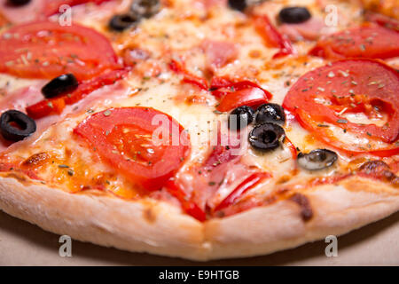 Una deliziosa pizza italiana con prosciutto, pomodori e olive, il fuoco selettivo Foto Stock