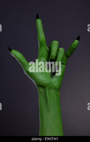 Mano verde con unghie nere che mostra heavy metal gesto, studio shot su sfondo nero Foto Stock