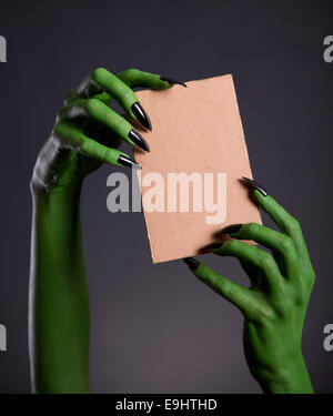 Green monster mani tenendo vuoto pezzo di cartone, tema Halloween Foto Stock