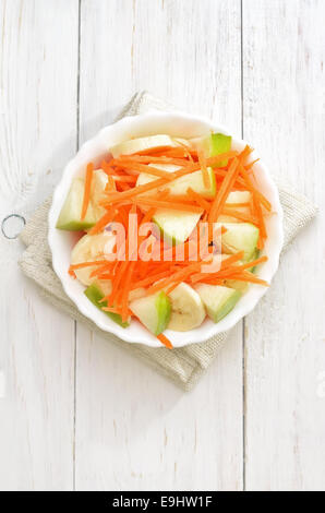 Miscugli di frutta verdura con Insalata di carote, mele, banane nella ciotola di legno bianco tabella, vista dall'alto Foto Stock