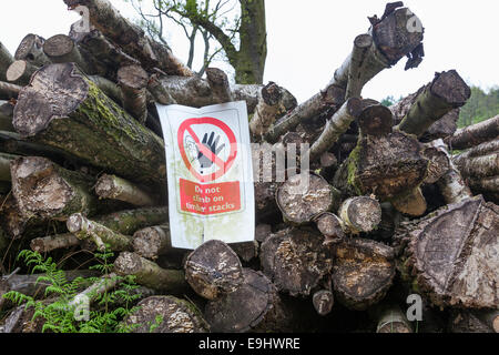 Pila di legname abbattuto log in una radura del bosco con un avviso di non salire sul legname. Foto Stock