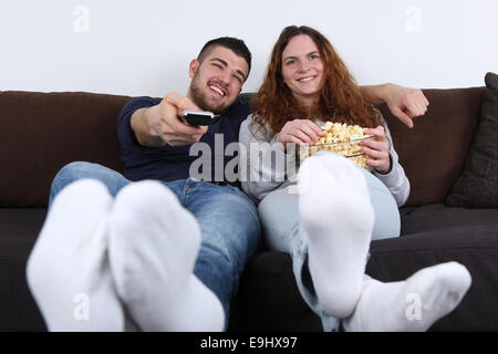 I giovani divertirsi mentre si guarda la TV e mangiare popcorn Foto Stock