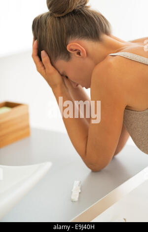 Primo piano sul test di gravidanza e frustrati giovane donna in background Foto Stock