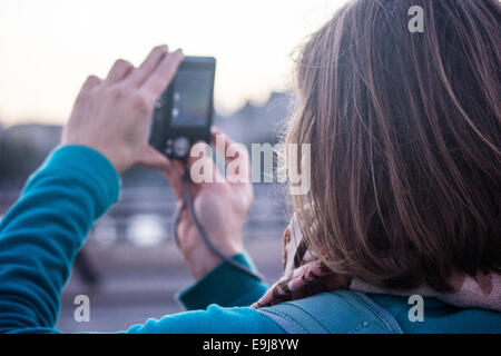 Turistica prendendo una foto su London Waterloo Bridge verso la London Eye e il Big Ben. Foto Stock