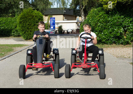 Due bambini che viaggiano su go kart a Sandford Holiday Park, Poole, Dorset, Regno Unito Foto Stock