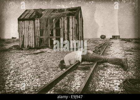 Surreale foto vintage di donna sdraiata su un binario ferroviario accanto a un felice segno Foto Stock