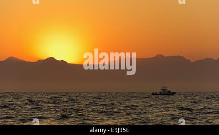 Orange sunrise all'oceano con montagne sagome Foto Stock