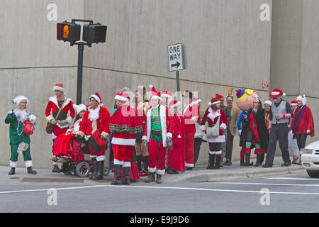 Un pacco di Babbo Natale, MRS. Le clausole e gli elfi attendere di attraversare una strada nel centro di Asheville intorno a Natale durante l'evento santacon Foto Stock