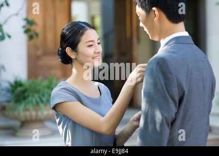 Giovane donna regolando il suo marito la cravatta Foto Stock