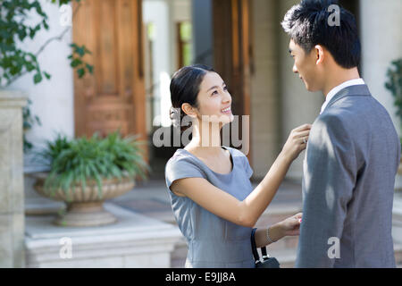 Giovane donna regolando il suo marito la cravatta Foto Stock