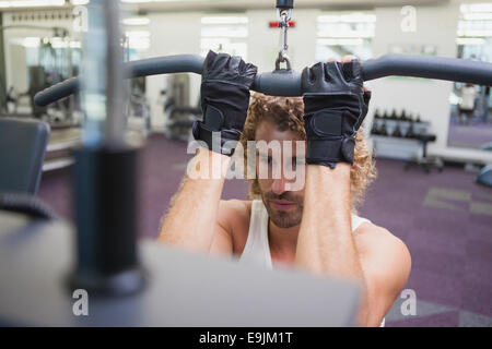 Giovane uomo che esercitano su una lat machine in palestra Foto Stock