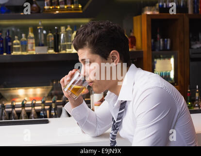 Giovane uomo di bere whisky neat Foto Stock