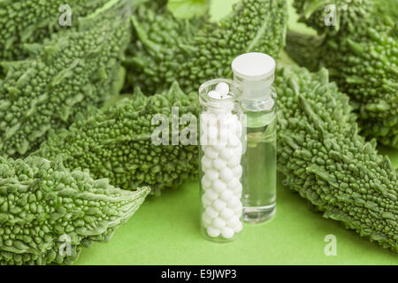 Un concetto di omeopatia con la medicina omeopatica nella foto insieme con zucche amare che hanno usi omeopatici. Foto Stock