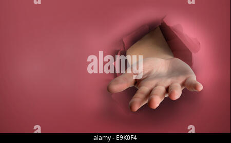 Immagine composita di mano lo scoppio attraverso la carta Foto Stock