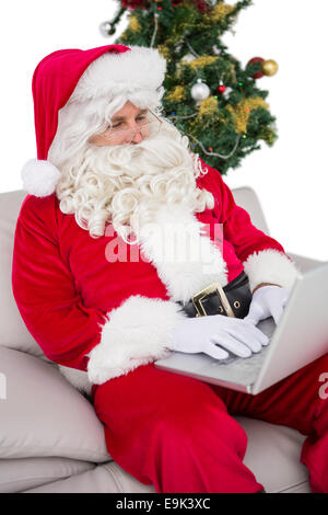 Babbo Natale utilizzando computer portatile sul divano Foto Stock