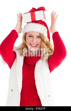 Donna sorridente bilanciamento regalo di Natale sulla sua testa Foto Stock