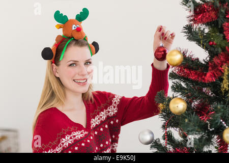 Donna Appendere le decorazioni di Natale su albero Foto Stock