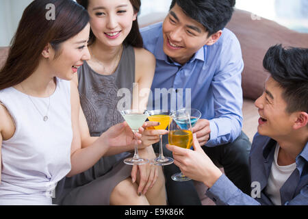 Felice giovani amici bevendo un cocktail nel salotto Foto Stock