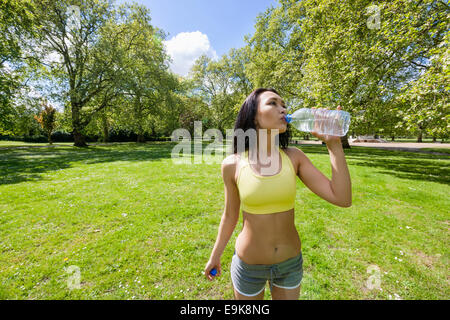 Montare la giovane donna acqua potabile dopo un po' di jogging nel parco Foto Stock