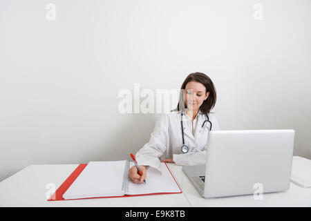 Medico donna iscritto sul legante alle escursioni in clinica Foto Stock