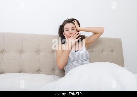 Assonnato donna sbadigli nel letto Foto Stock