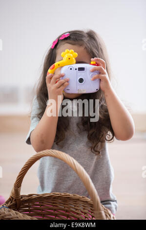 Bambina fotografando attraverso la fotocamera giocattolo a casa Foto Stock