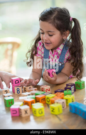 Felice ragazza che gioca con blocchi di alfabeto a tavola Foto Stock