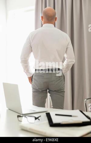 Vista posteriore di imprenditore in piedi in home office Foto Stock