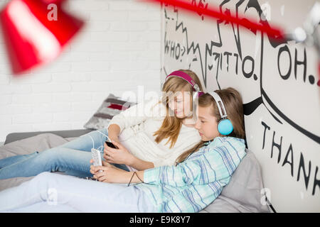 Sorelle rilassati ascoltando la musica a casa Foto Stock