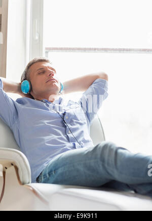 Rilassata uomo di mezza età ascoltando la musica a casa Foto Stock