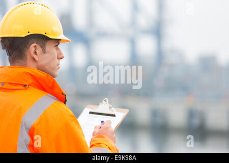 Vista posteriore della metà uomo adulto iscritto negli appunti nel cantiere di spedizione Foto Stock