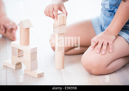 Sezione mediana della ragazza che gioca con la costruzione di blocchi su pavimento in legno duro Foto Stock