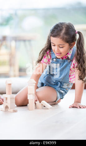 Bambina di blocchi di costruzione mentre è seduto sul pavimento di legno duro Foto Stock