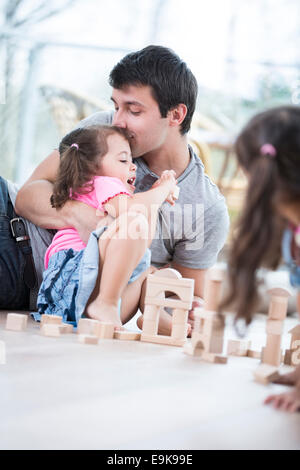 Padre amorevole figlia baciando la costruzione di blocchi sul pavimento Foto Stock