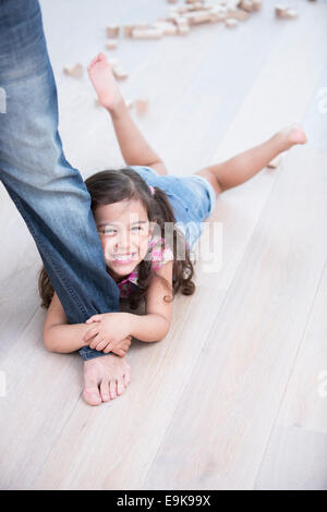 Ritratto di felice ragazza essendo trascinato dal padre su pavimento in legno duro Foto Stock