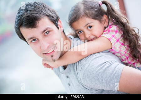 Vista laterale ritratto di uomo sorridente piggybacking piccola figlia a casa Foto Stock