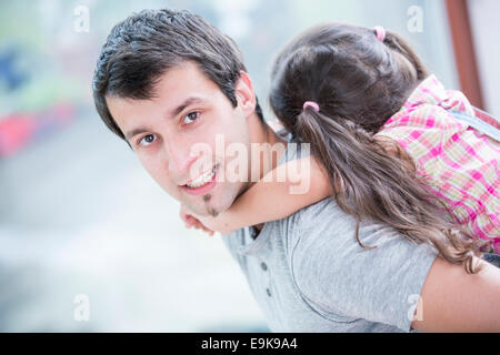 Vista laterale Ritratto di giovane uomo piggybacking piccola figlia a casa Foto Stock