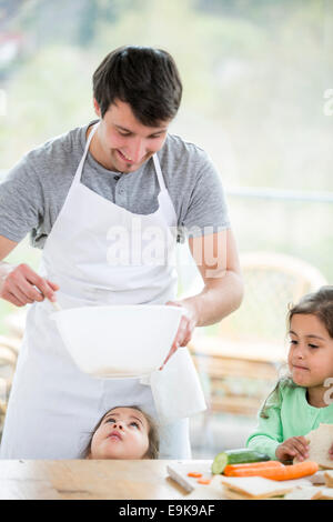 Padre sorridente la preparazione di sandwich con le figlie a casa Foto Stock