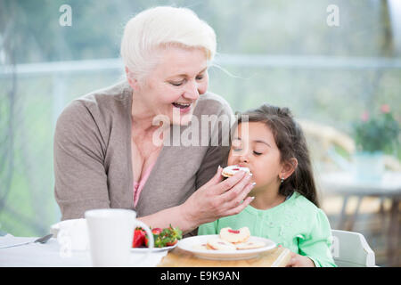 Felice senior alimentazione donna cookie al nipote a casa Foto Stock