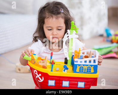 Carina ragazza che gioca con la nave giocattolo a casa Foto Stock