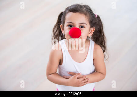 Ritratto di carino bambina indossa un clown naso a casa Foto Stock