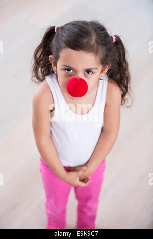 Ritratto di carino bambina indossa un clown naso a casa Foto Stock