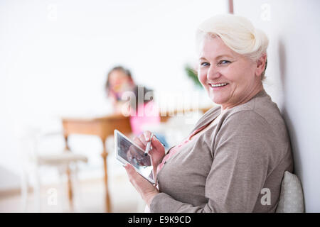 Ritratto di felice donna senior con tavoletta digitale con stilo a casa Foto Stock