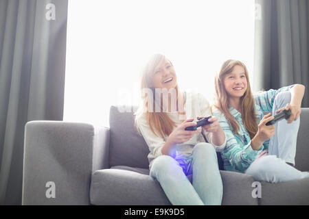 Sorelle di giocare con i videogiochi su divano Foto Stock