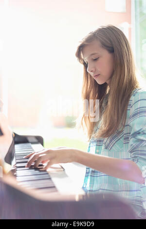 Vista laterale di una ragazza suonare il pianoforte a casa Foto Stock