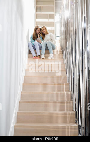 Lunghezza intera di sorelle ascoltando musica su scala Foto Stock