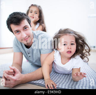 Ritratto di Padre con le figlie giacente su una coperta a casa Foto Stock