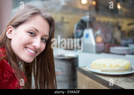 Ritratto di donna felice da vetrina in cafe Foto Stock