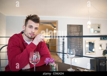 Ritratto di fiducioso giovane uomo di bere acqua dal vetro in cafe Foto Stock